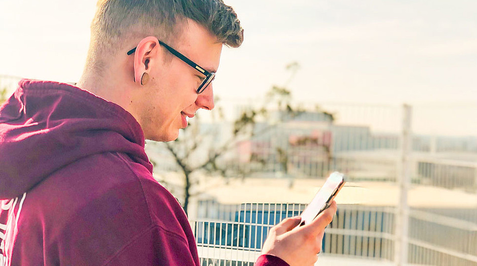 Ein junger Mann sieht auf sein Smartphone