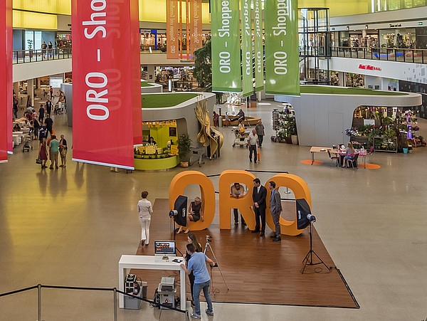 Innenansicht der Shopping Mall. Großes, lichtdurchflutetes, modernes Gebäude mit Ladengeschäften, Ständen, Banner und vielem mehr.