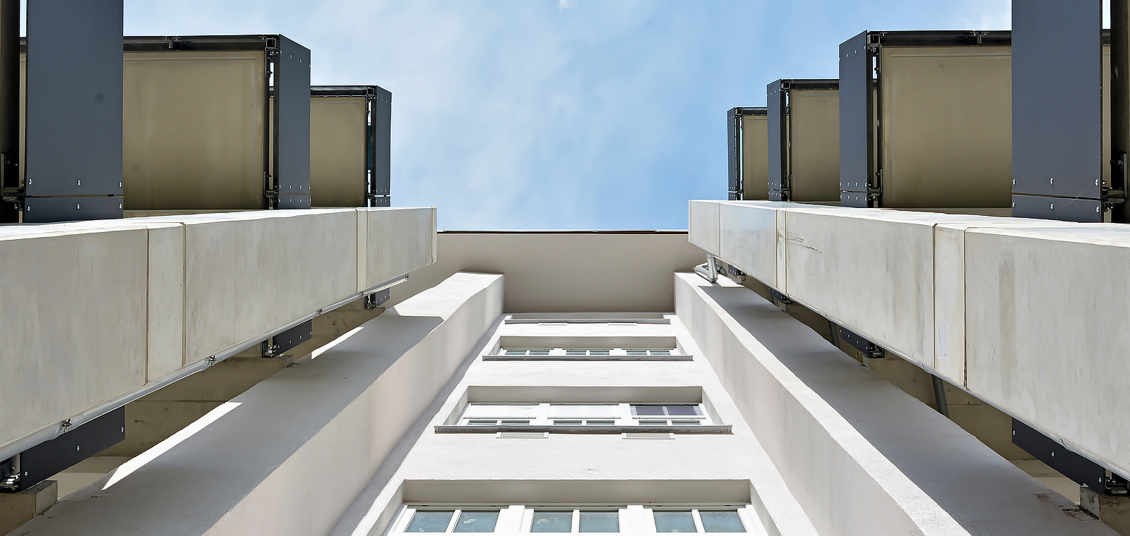 Ein von unten fotografierter Altbau, der saniert und um moderne Balkone ergänzt wurde.