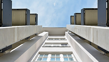 Ein von unten fotografierter Altbau, der saniert und um moderne Balkone ergänzt wurde.