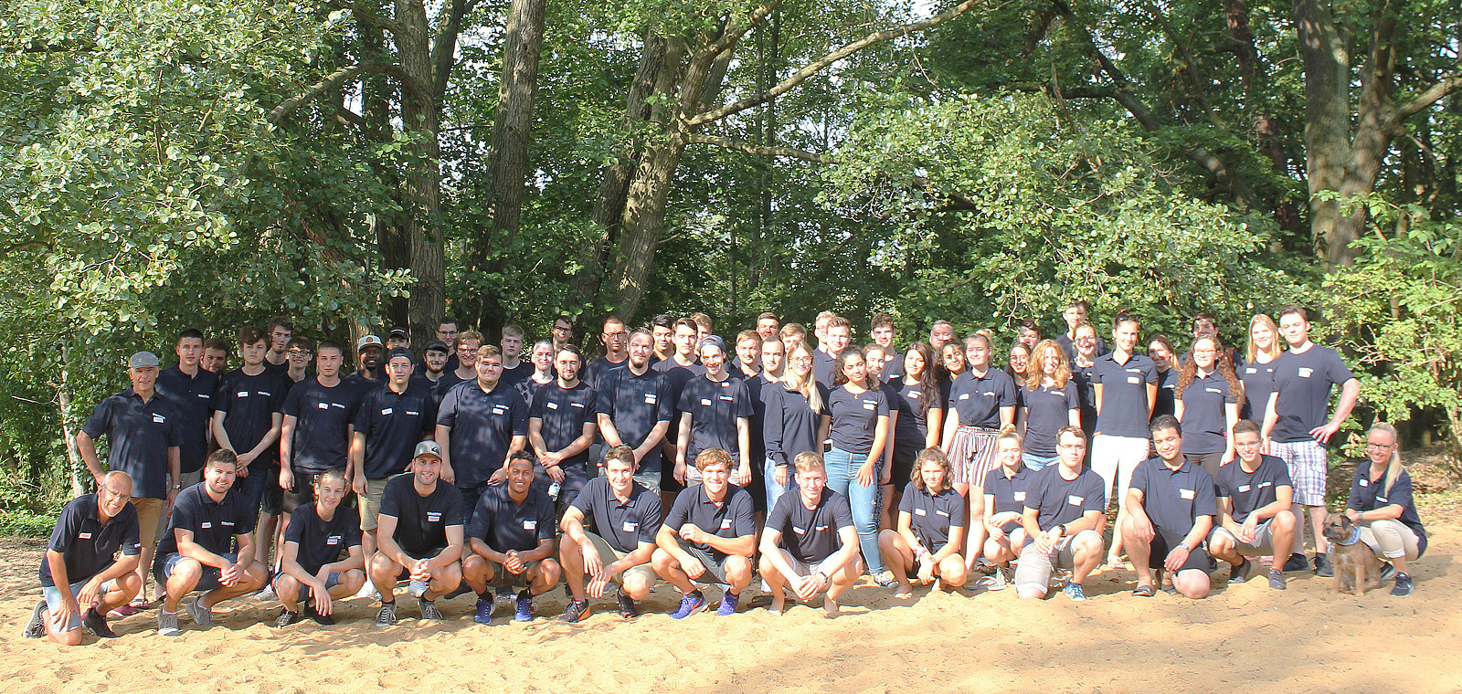 Viele junge Menschen posieren für ein gemeinsames Gruppenfoto.