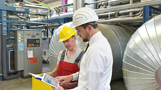 Qanteon, eine Software für Techniker, Controller und Energiemanager Zwei Männer unterhalten sich über Werte auf dem Tablet